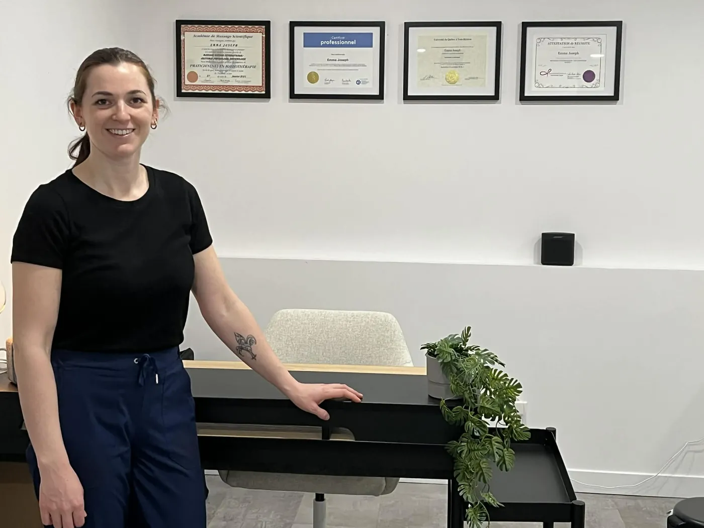 Emma Joseph dans son local, devant ses quatre diplômes encadrés